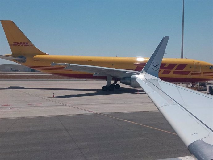 Archivo - Detalle de un avión de transporte de mercancías, al fondo, estacionado en el aeropuerto hispalense.