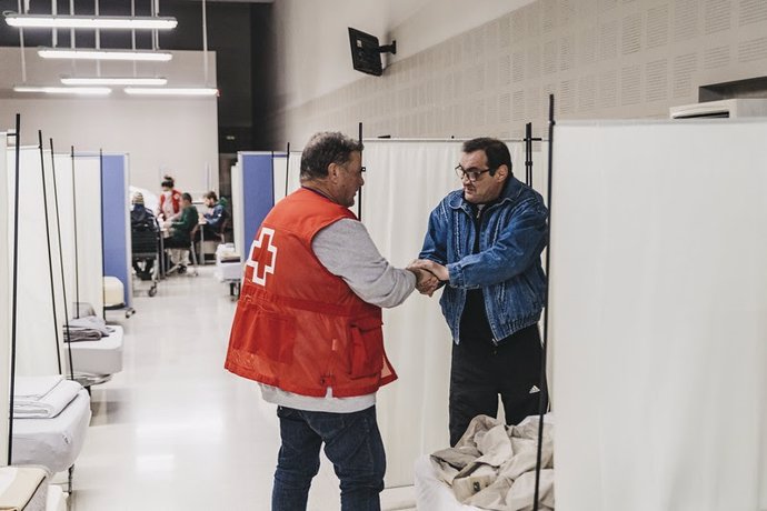 Un voluntario de Crus Roja atiende a una persona en situación de sinhogarismo en un recurso.