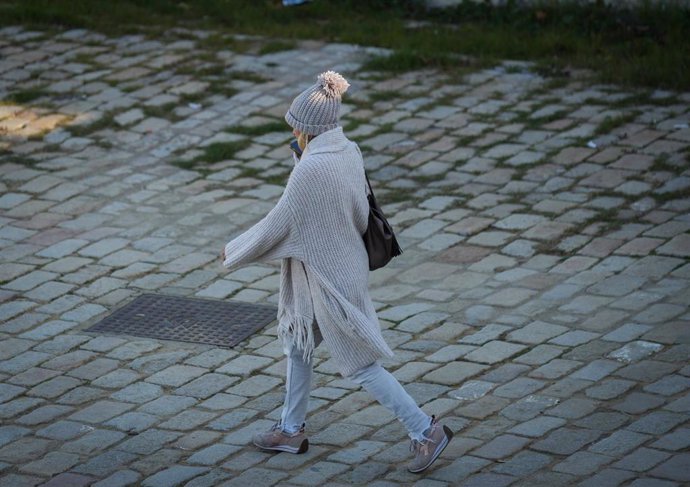 Una mujer abrigada pasea por la calle