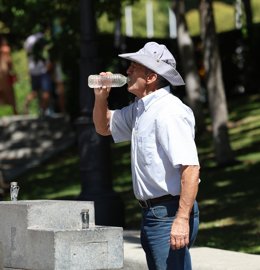 Archivo - Un hombre llena una botella de agua de una fuente, durante una segunda ola de calor, a 23 de julio de 2024, en Madrid (España). 