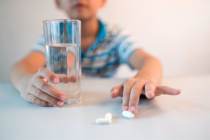 Archivo - Niño tomando medicamentos con vaso de agua.