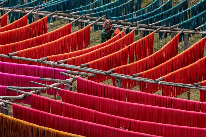 Archivo - 04 April 2021, India, Shantipur: A labourer hangs fabric threads to dry after their dyeing at a dyeing factory. Photo: Saurabh Sirohiya/ZUMA Wire/dpa