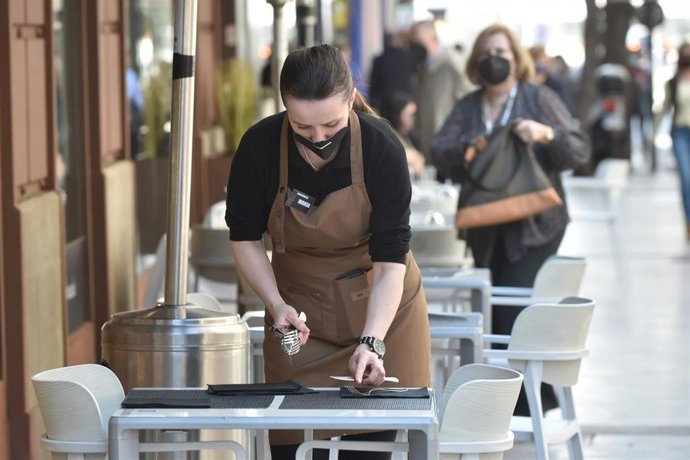 Archivo - Una camarera prepara una mesa en la terraza de un restaurante.