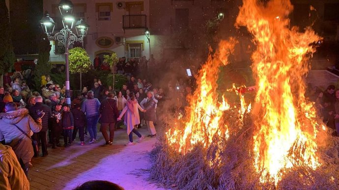 Lumbre oficial de San Antón 2025, junto a la que un grupo de personas baila melenchones.