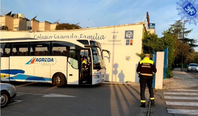 Agentes de la Policía Local llevan a cabo la inspección de un autobús de transporte escolar junto al colegio Sagrada Familia de Zaragoza, en imagen de archivo.