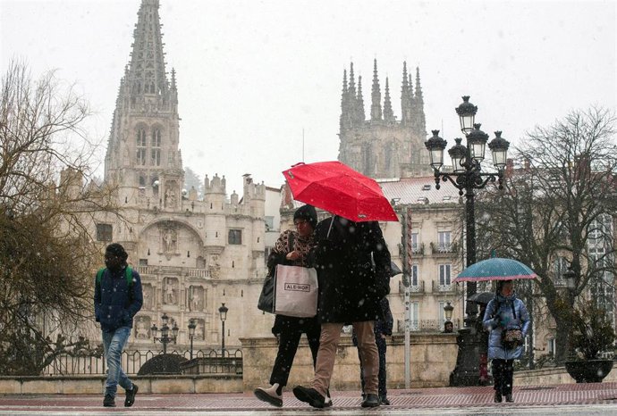 Archivo - Varias personas caminan por la calle mientras nieva, a 23 de febrero de 2023, en Burgos, Castilla y León (España).