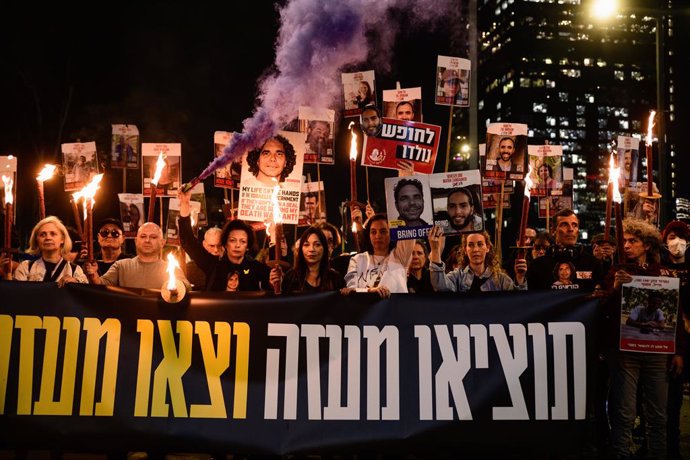 January 15, 2025, Tel Aviv, Israel: Ifat Kalderon, cousin of Israeli hostage Ofer Kalderon holds up a smoke flare and a sign with Ofer's photo next to supporting protestors with hostages photos and flares, the sign reads ''Get them out of Gaza, and get ou