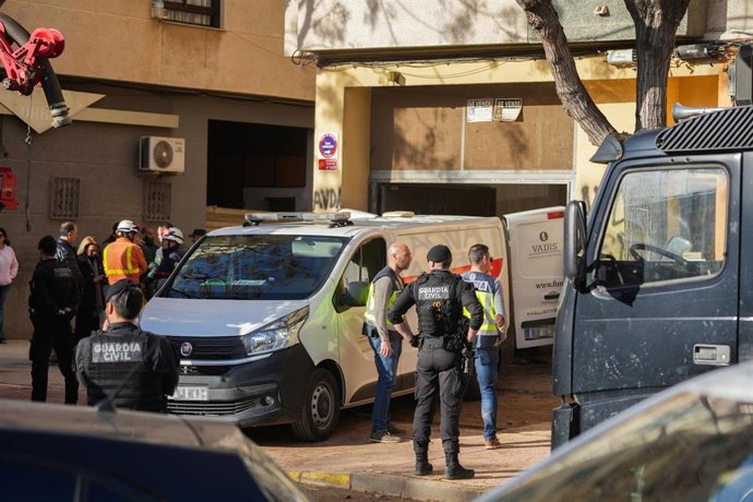 Varios agentes de la Guardia Civil y de la Policía junto a un vehículo funerario en el lugar de los hechos, a 18 de enero de 2025, en Benetússer, Valencia, Comunidad Valenciana (España).