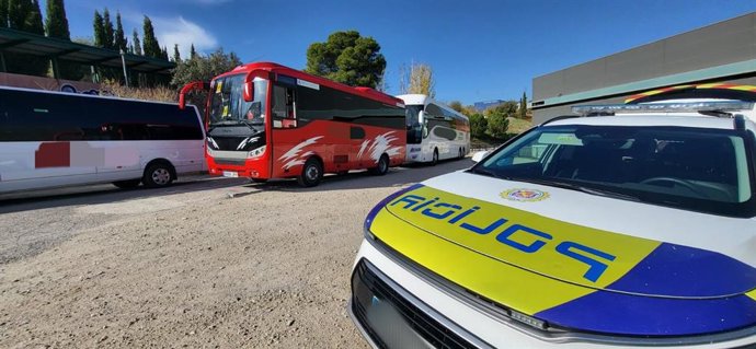 Vehículo de la Policía Local junto a un autobús.