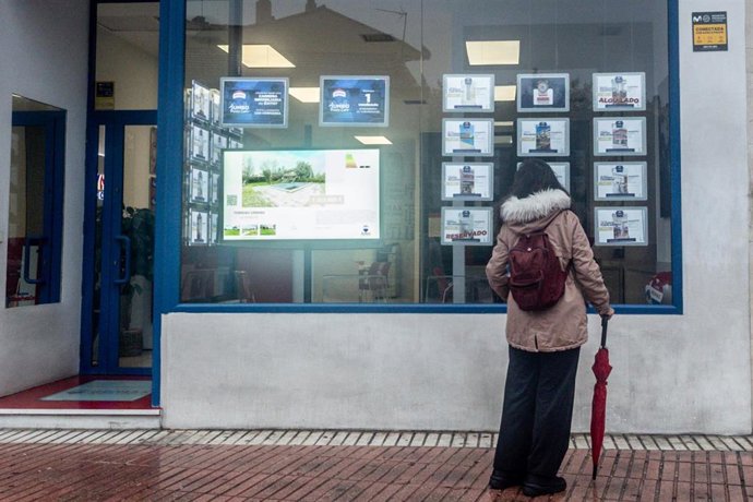 Archivo - Una mujer observa las ofertas de una inmobiliaria