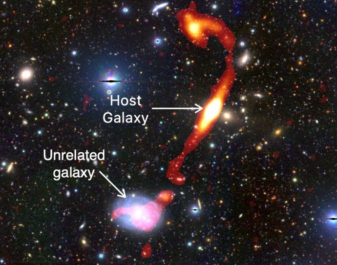 La recién descubierta galaxia gigante de radio 'Inkathazo'. Los brillantes chorros de plasma, vistos por el telescopio MeerKAT, se muestran en rojo y amarillo. La luz de las estrellas de otras galaxias circundantes se puede ver en el fondo.