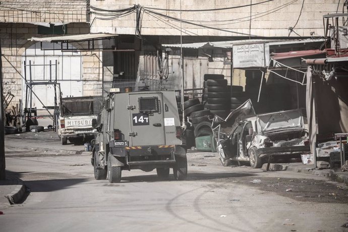 January 10, 2025, Jenin, West Bank, Palestine: An Israeli military vehicle drives past a destroyed Palestinian vehicle that was damaged by the Israeli army in the town of Qabatiya, south of the northern West Bank city of Jenin. The Israeli military said t