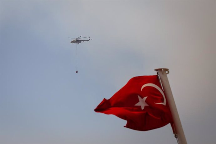 Archivo - Imagen de archivo de un helicóptero de los Bomberos detrás de una bandera de Turquía