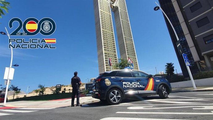Archivo - Un agente junto a un coche de Policía Nacional en Benidorm (Alicante), en una imagen de archivo.