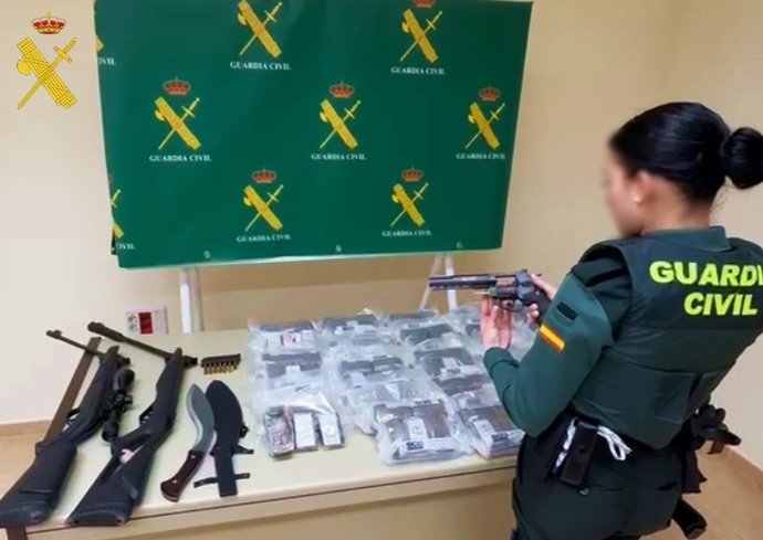 Una agente de la Guardia Civil de Almería revisa las armas y el material incautado.