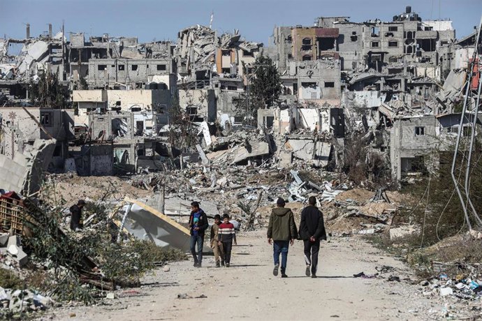 Un grupo de palestinos camina entre edificios destruidos por los ataques del Ejército de Israel contra el campamento de refugiados de Bureij, en Deir al Balá, situada en el centro de la Franja de Gaza