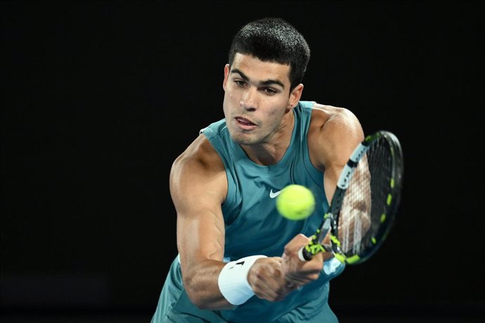 21 January 2025, Australia, Melbourne: Spanish tennis player Carlos Alcaraz hits a backhand return against Serbia's Novak Djokovic during their men's singles quarterfinal tennis match on day ten of the Australian Open tennis tournament at Melbourne Park. 