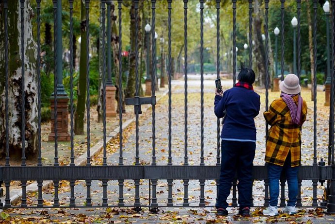 Archivo - Turistas en las rejas cerradas del Parque de María Luisa. Imagen de archivo. 
