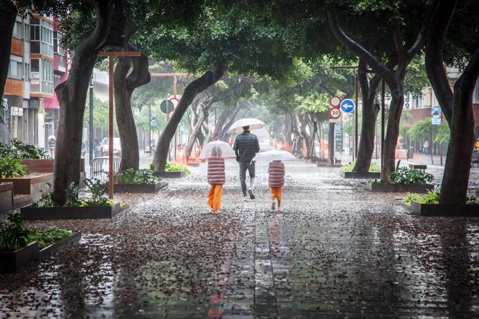 Archivo - Varias personas se cubren de la lluvia con un paraguas mientras caminan por una vía, a 25 de septiembre de 2022, en Las Palmas de Gran Canaria, Canarias (España). El Gobierno de Canarias ha pedido evitar desplazamientos durante este fin de seman