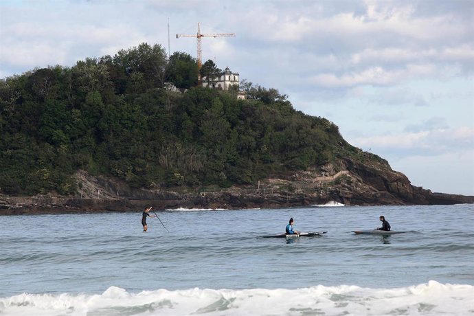 Archivo - Varias personas reman en canoas junto a la playa de La Concha
