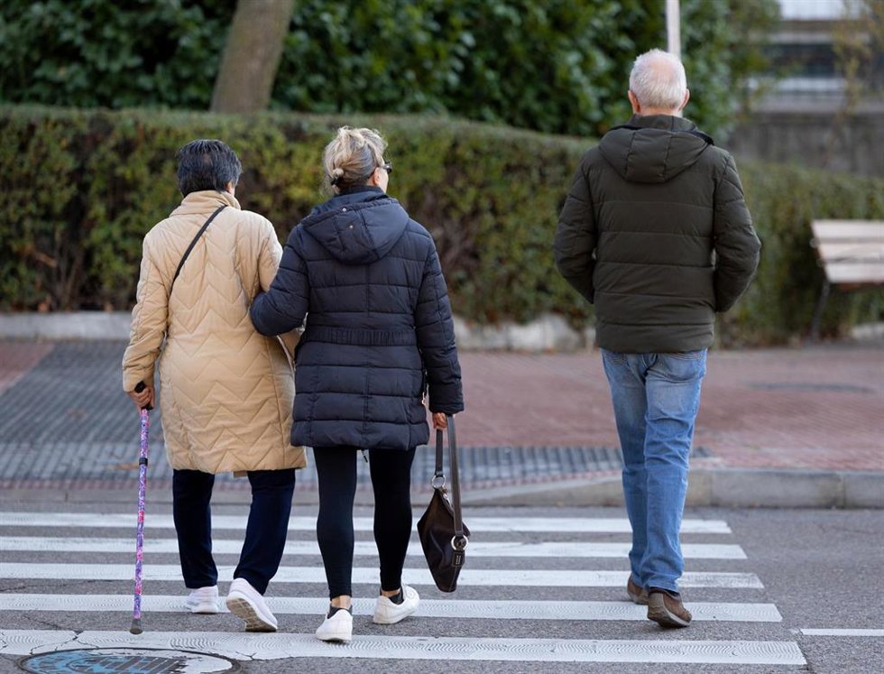 Varias personas, entre ellas una mujer pensionista, cruzando una calle