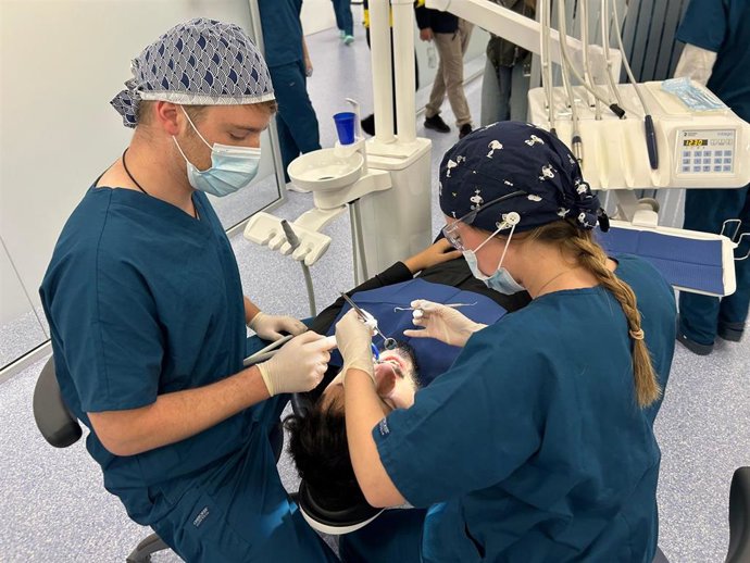 Tres estudiantes de quinto curso de Odontología con un paciente durante una práctica
