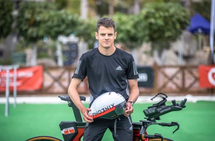 El triatleta británico Jonathan Brownlee posa con su casco y bici para la prueba.