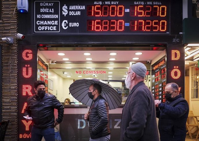 Archivo - 17 December 2021, Turkey, Istanbul: People walk in front of a currency exchange shop in Istanbul. The Turkish central bank cut its benchmark interest rate to 14 per cent on Thursday, the fourth consecutive cut since September, leading the lira t