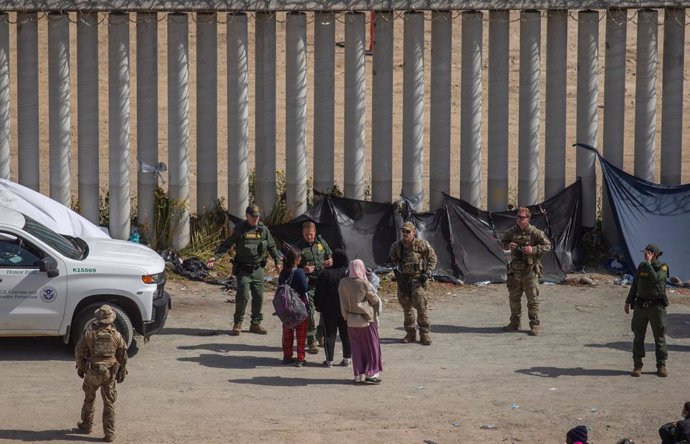 Archivo - 09 May 2023, Mexico, Tijuana: Migrants talk with US security forces in the area between the two walls that separate Mexico from the United States. Many migrants are hoping to be allowed to immigrate to the US more easily after the "Title-42" dep