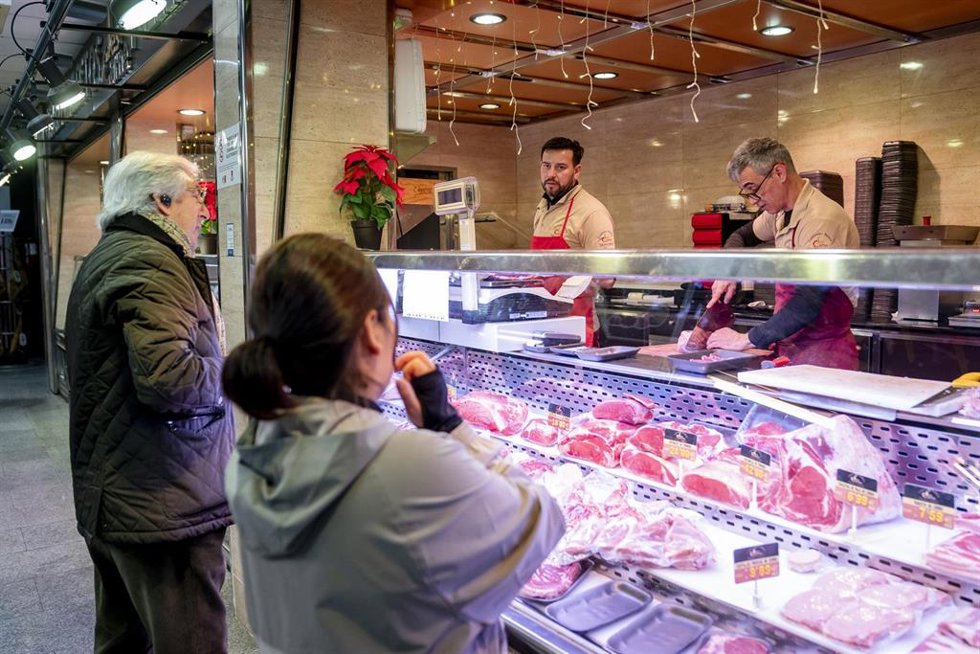 Varias personas hacen compras en un mercado.