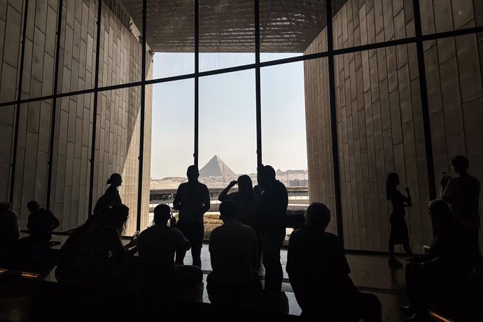 Archivo - 15 October 2024, Egypt, Giza: Visitors stand by a window overlooking the Pyramids of Giza, at the Grand Egyptian Museum (GEM) in Giza. A partial soft opening of the Grand Egyptian Museum will start on Wednesday, October 16, with a trial operatio