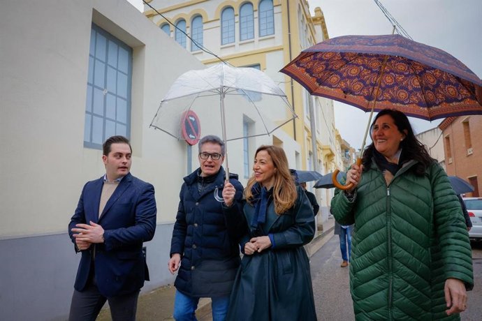 La alcaldesa de Zaragoza, Natalia Chueca, protegida de la lluvia por el consejero municipal de Urbanismo, Víctor Serrano, junto a la concejala delegada de Barrios Rurales, Paloma Espinosa, y el alcalde de Casetas, Jorge Eseverri, en la Harinera.