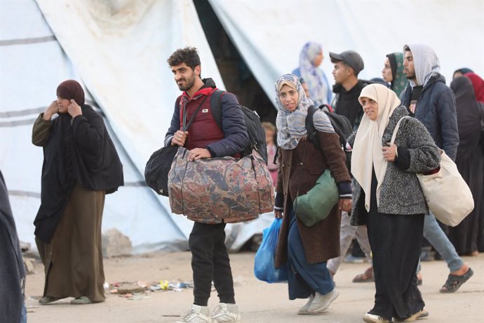 January 26, 2025, Nusairat, Gaza Strip, Palestinian Territory: Palestinians, who were forcibly displaced as a result of Israel's attacks on the Gaza Strip for more than 15 months, wait with their belongings at a point close to the Netzarim Corridor on al-