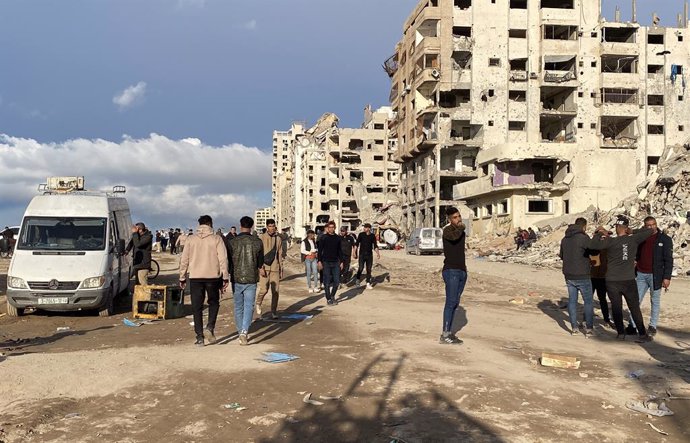 January 26, 2025, Gaza City, Gaza Strip, Palestinian Territory: People gather by a banner welcoming people near the rubble of a collapsed building along Gaza's coastal al-Rashid Street for people to cross from the Israeli-blocked Netzarim corridor from th