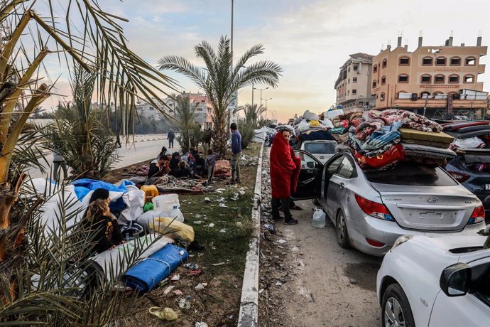 26 January 2025, Palestinian Territories, Gaza: Displaced Palestinians wait along Salah al-Din Road in Nuseirat, near the blocked Netzarim corridor, to cross to the northern part of the Gaza Strip. Many spent the night near the corridor, waiting for the r