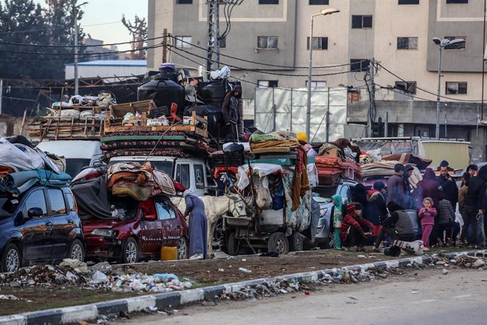 26 January 2025, Palestinian Territories, Gaza: Displaced Palestinians wait along Salah al-Din Road in Nuseirat, near the blocked Netzarim corridor, to cross to the northern part of the Gaza Strip. Many spent the night near the corridor, waiting for the r