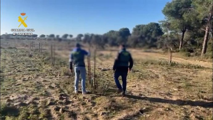 Una pareja de agentes junto a tutores de alcornoques de una finca forestal en Aznalcázar.