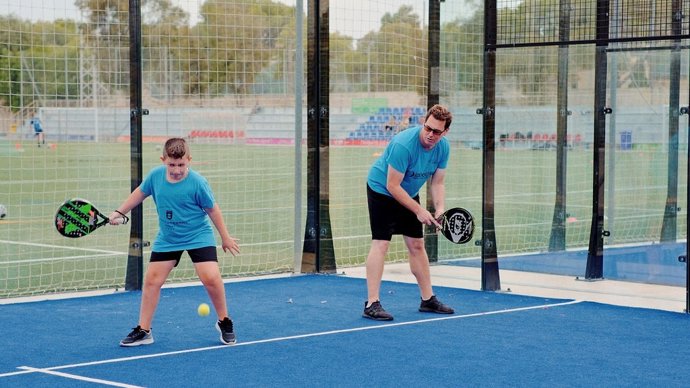 Un niño y un hombre juegan a pádel en el polideportivo de Sant Ferran.
