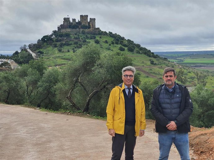 El delegado de Infraestructuras, Sostenibilidad y Agricultura de la Diputación, Andrés Lorite (izda.), y el alcalde de Almodóvar del Río, Ramón Hernández, visitan el camino 'De la Peña del Águila' con el castillo al fondo.