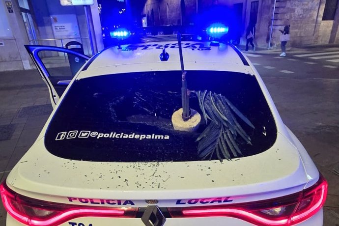 Coche patrulla de la Policía Local de Palma con la luna rota por la agresión del detenido.