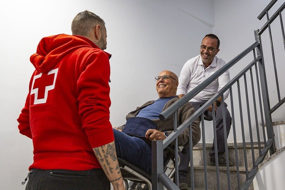 Miembros de Cruz Roja ayudando a subir a persona en silla oruga en un municipio afectado por la dana