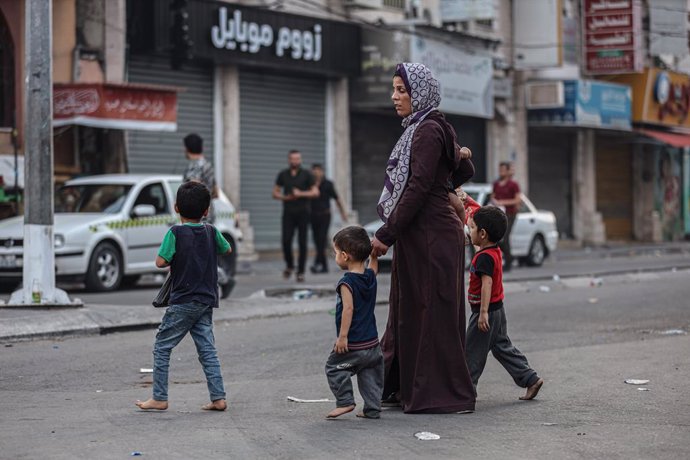 Archivo - Una mujer cruza una calle de Gaza con sus hijos.