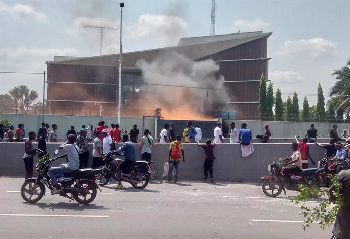 January 28, 2025, Kinshasa, Congo: Street scene with people watching the flames of some burning tyres at the entrance of the Belgian embassy building in Kinshasa, DRC Congo, Tuesday 28 January 2025. Demonstration broke out to protest against the violence 