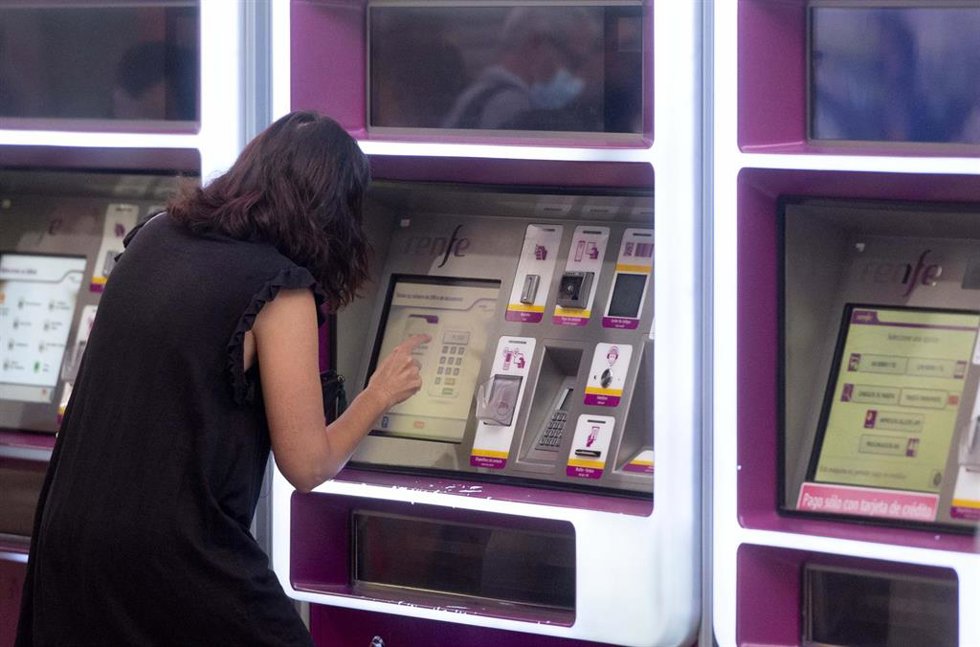Archivo - Una mujer compra su billete en las taquillas de venta automática de la estación de tren de Atocha