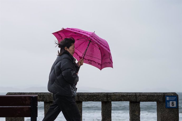 Una mujer se refugia de la lluvia con paraguas en la comarca de Salnés, a 27 de enero de 2025, en Salnés, Pontevedra, Galicia (España). La borrasca 'Herminia' recorre la Península hoy y llegará hasta el Mediterráneo y Baleares al final del día cuando se p