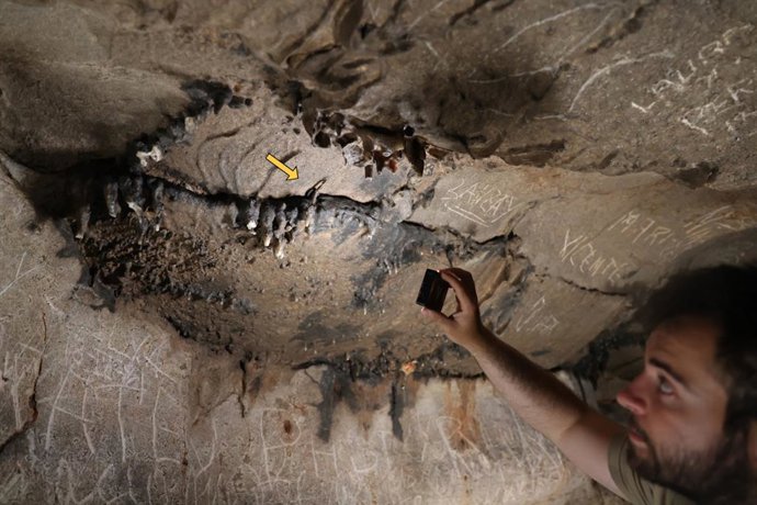 El investigador Xabier Garín Artázcoz señala el lugar exacto de la cavidad en el que se halló la moneda romana de la época del emperador Claudio.