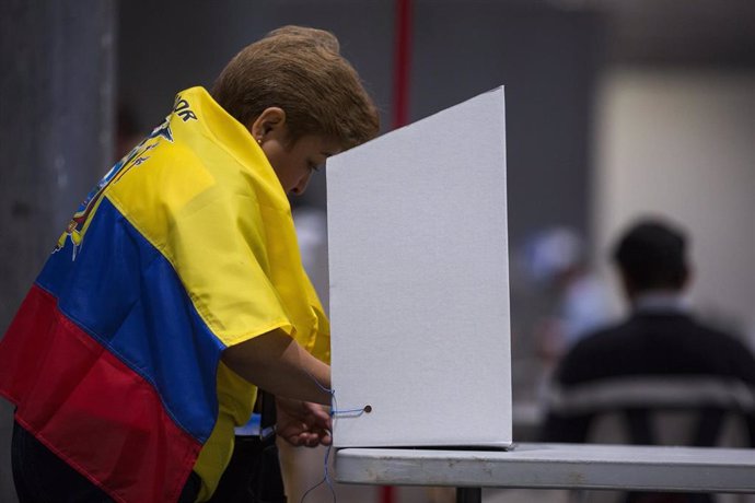 Archivo - Una mujer con una bandera ecuatoriana votando en las últimas elecciones desde Madrid.