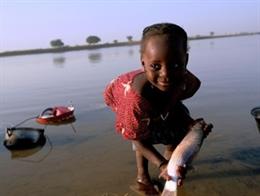 Una niña de la aldea de Diafarabe Fulani, a orillas del río Níger, limpia su ropa y un pescado para el almuerzo.