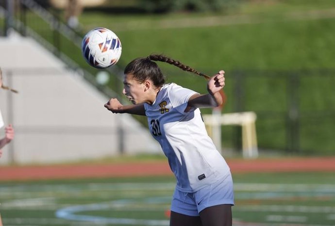 Archivo - Jugador de fútbol de la Universidad de Rochester cabecea el balón.