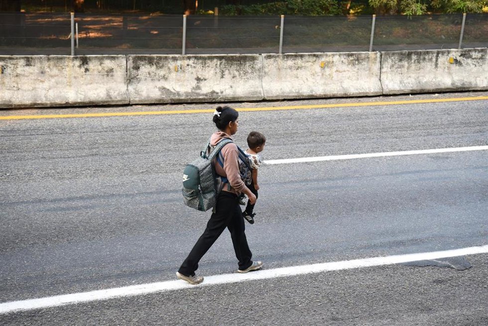 20 January 2025, Mexico, Huehuetan: A woman carries her child on the side of a country road in the hope of reaching the US border. 